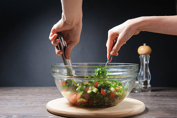 Girl stirs cooked vegetarian vegetable salad