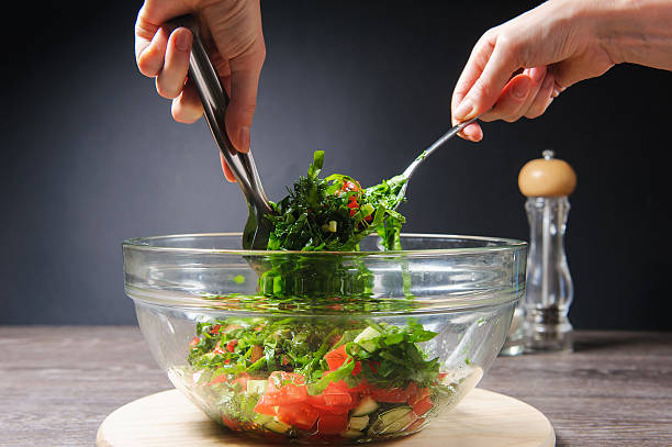 Girl stirs cooked vegetarian vegetable salad