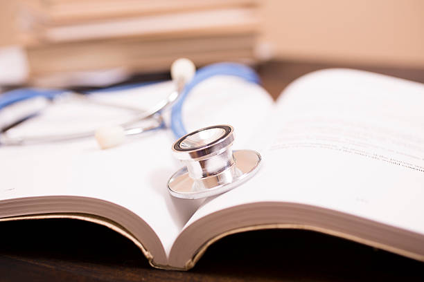 istock Doctor's stethoscope on desk with open books to study, read. 584790560