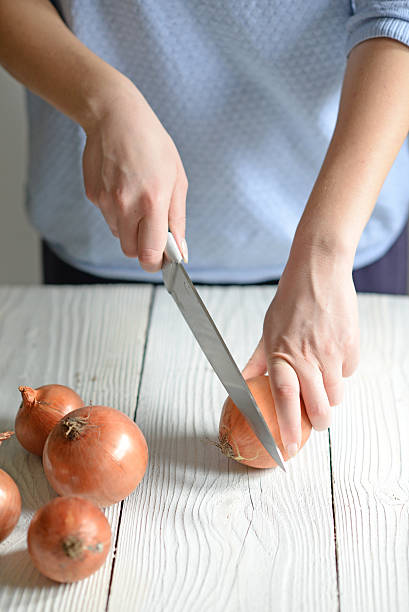 istock Woman hand cut fresh onion on white table 584846536