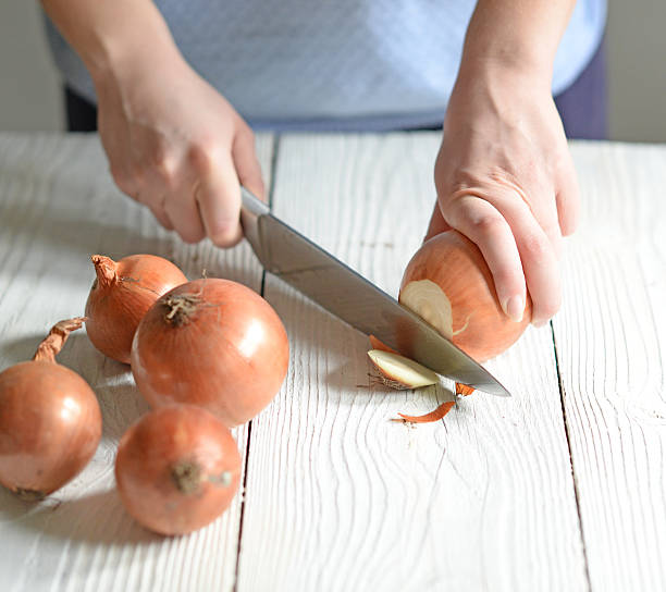 istock Woman hand cut fresh onion on white table 584846692