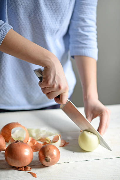 istock Woman hand cut fresh onion on white table 584846812