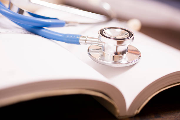 istock Doctor's stethoscope on desk with open books to study, read. 584848732