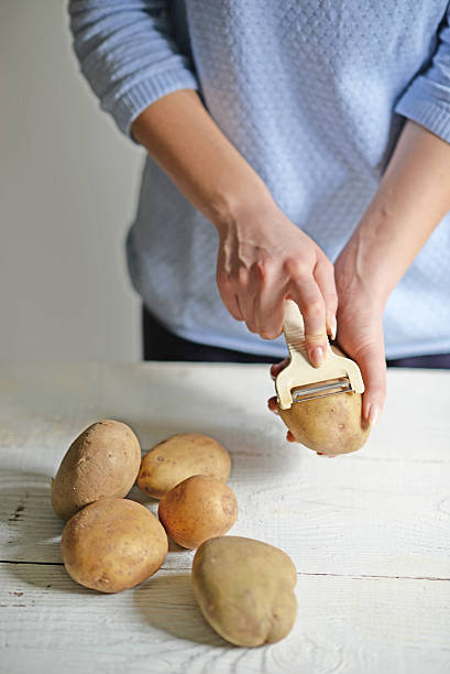 istock Woman hands peeling potatoes for boiling 584851578