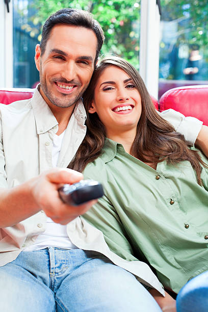 istock Happy young couple watching TV on sofa 584853200