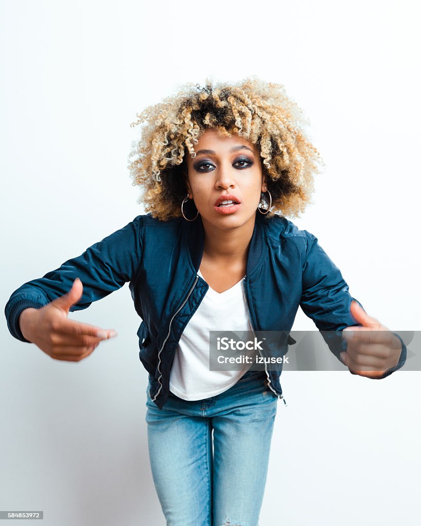 Portrait of afro american young woman Portrait of afro american young woman wearing bomber jacket, denim trausers, looking at camera. Rap Stock Photo