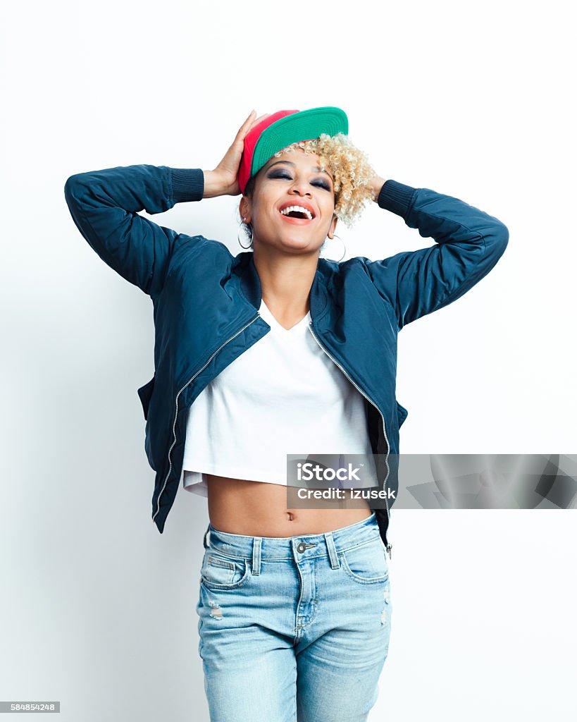 Portrait of happy afro american young woman with baseball cap Portrait of happy afro american young woman wearing bomber jacket, denim trausers and baseball cap. One Woman Only Stock Photo