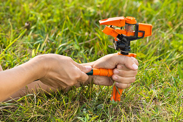 istock hands installing garden sprinkler for irrigation of lawn 584856062