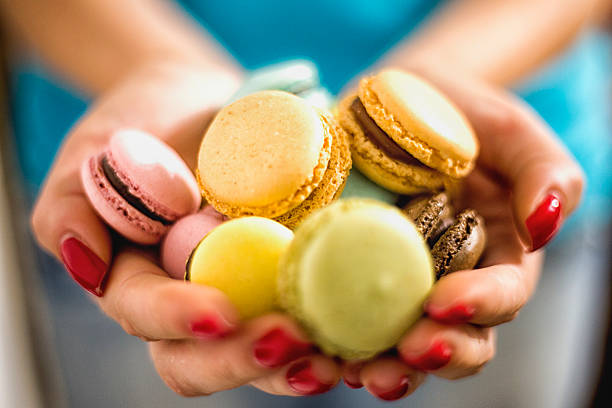 deliciosos biscoitos macaroons na mão das mulheres - cake yellow sweet food banquet - fotografias e filmes do acervo