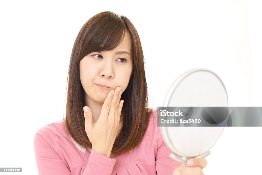Disappointed Asian woman Asian woman looking at her face in mirror Japanese Ethnicity Stock Photo