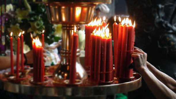 istock Hand Lighting Up Candle Rack In Temple 584859156