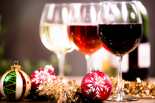 Wine tasting event at Christmas party. Red, rose and white wine selections on an outdoor patio table with holiday decorations.  Wine bottles in background.  Rustic wooden table.  No people.