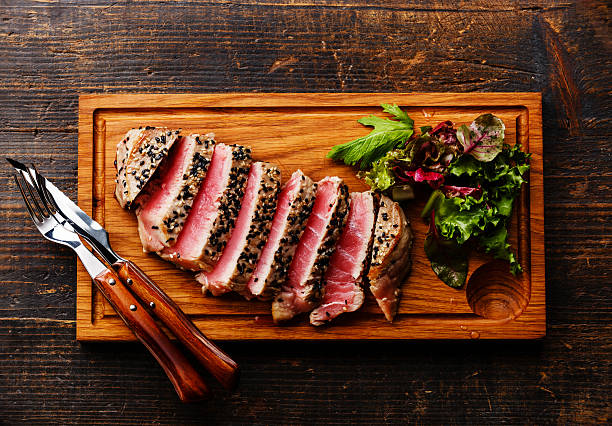 Tuna steak and Green salad Grilled Tuna steak in sesame and Green salad on wooden board on dark wooden background sesame stock pictures, royalty-free photos & images