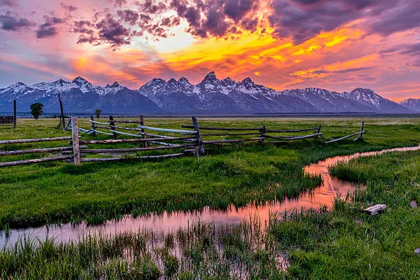 A colorful spring sunset at Teton Range, seen from an abandoned old ranch in Mormon Row historic district, in Grand Teton National Park, Wyoming, USA. 