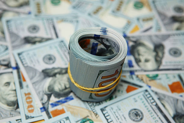 istock dollar roll on background of many dollars 584865022