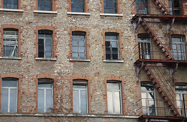 istock dilapidated industrial building with rusty fire escape with red 584865336