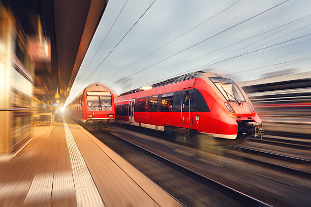 Modern high speed red passenger trains at sunset. Railway station Modern high speed red passenger trains at sunset. Railway station in Nuremberg, Germany. Railroad with motion blur effect. Industrial concept landscape passenger train stock pictures, royalty-free photos & images