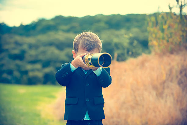 istock Young boy in a business suit with telescope. 584867762