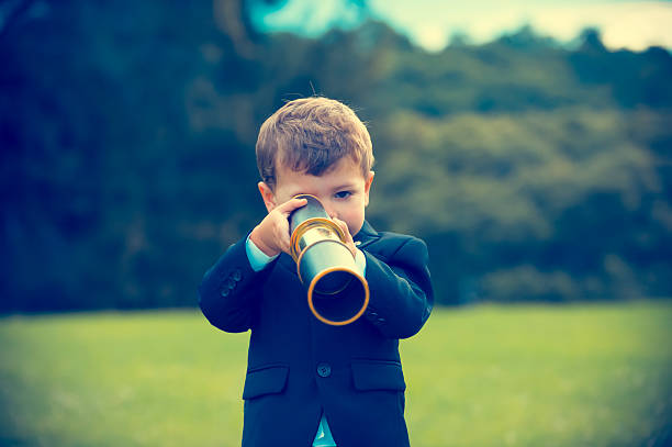 istock Young boy in a business suit with telescope. 584867850