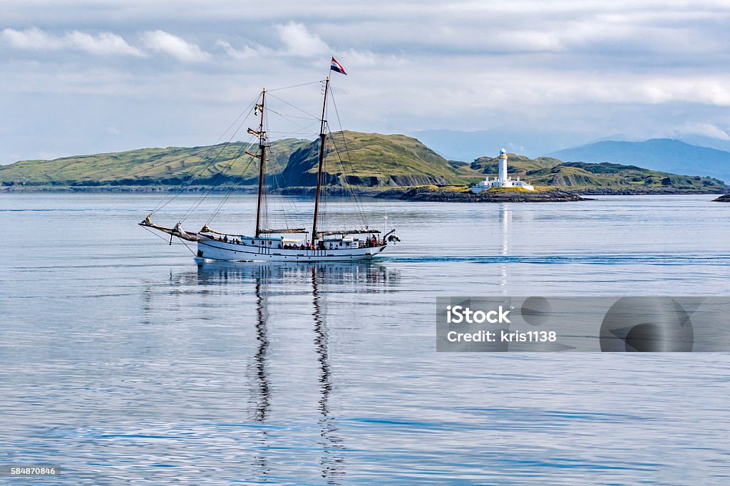 Sailing Boat in front of Eilean Musdile Lighthouse Just off Lismore Island between Oban and Isle of Mull Lismore - Scotland Stock Photo
