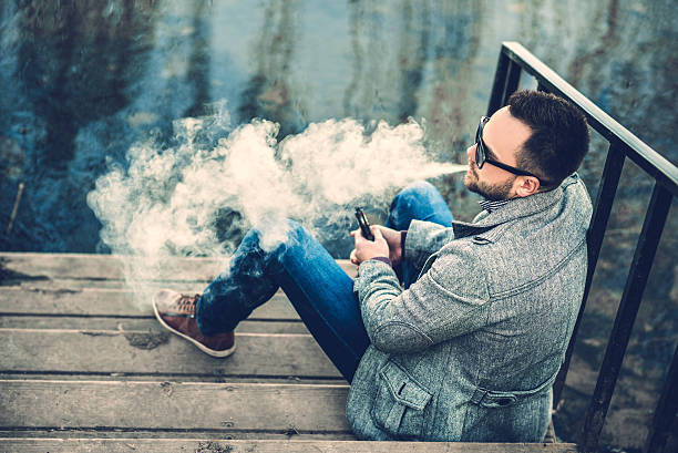 Man with beard vaping outdoor electronic sigarette stock photo