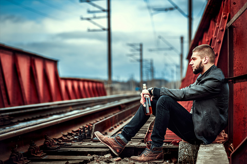 Young man with beard sitting on the railway