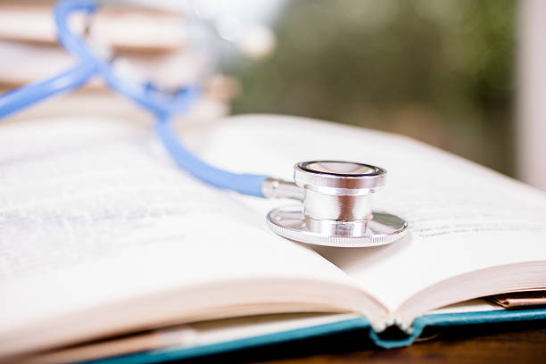 istock Doctor's stethoscope on desk with open books to study, read. 584871856