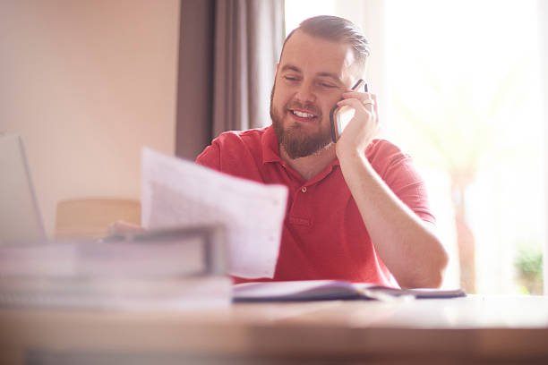 happy male on the phone with her mortgage company - declaring bankrupcy imagens e fotografias de stock