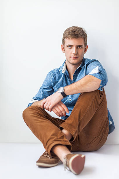 istock Handsome serious man sitting on the floor 584873618