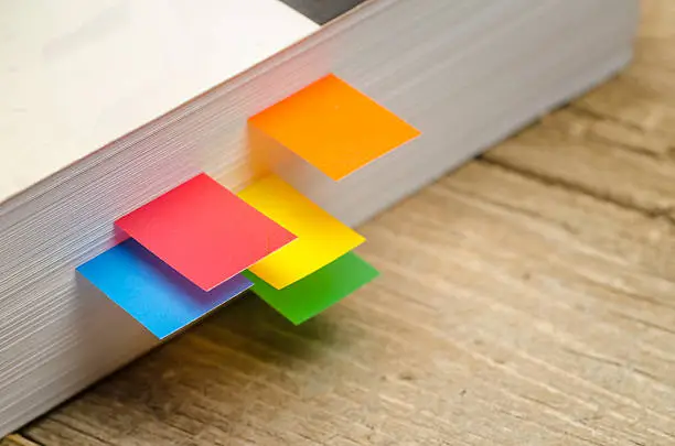 Close up shot of colorful bookmarks in paper back book - Stock Photo