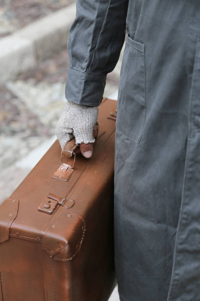 istock poor man with old leather suitcase and broken gloves 584876422