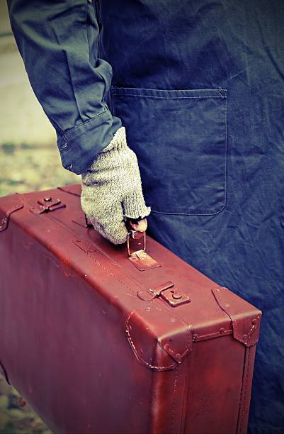 istock immigrant with old leather suitcase and the unstitched glove 584876626