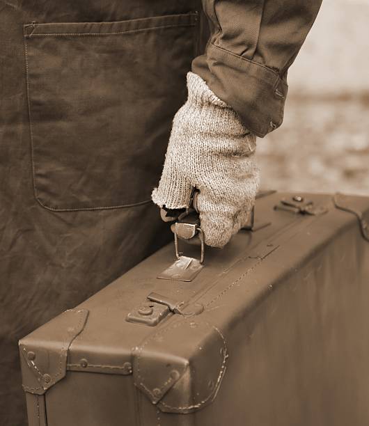 istock poor immigrant with old leather suitcase and the unstitched glov 584876706