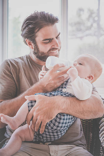 istock Modern Dad Feeding his Baby Boy with Milk Bottle 584879612