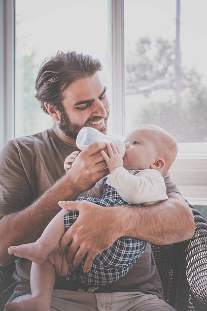 istock Modern Dad Feeding his Baby Boy with Milk Bottle 584879626