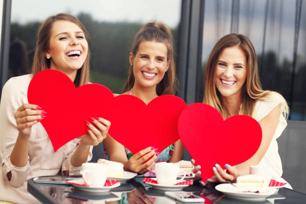istock Three girlfriends holding hearts in cafe 584879884