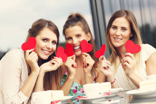 istock Three girlfriends holding hearts in cafe 584879986