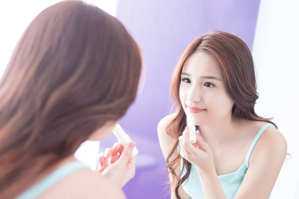 young woman painting  lip balm a young woman is  painting  lip balm in bathroom at home beatification stock pictures, royalty-free photos & images