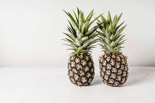 istock Pineapples on wooden table over white background 584885732