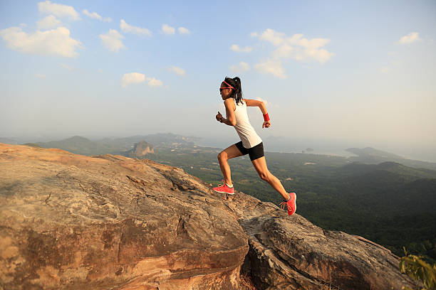 istock young asian woman runner running on mountain peak 584885780