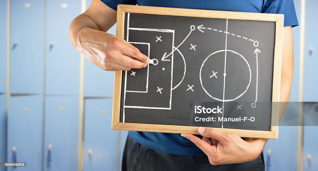 soccer tactics drawing on chalkboard hand of a football coach drawing a tactics of soccer game  with white chalk on blackboard at changing room Coach Stock Photo