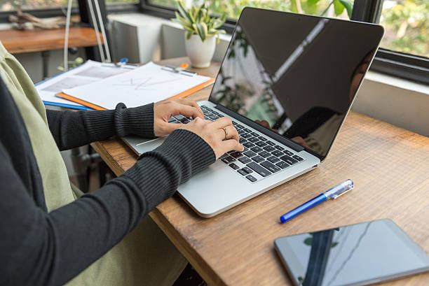istock Typing on laptop with document on wooden desk 585047438