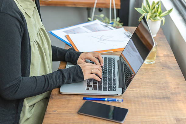 istock Typing on laptop with document on wooden desk 585048014