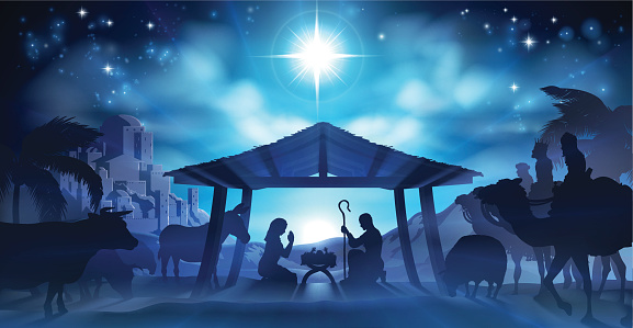 Christmas Nativity Scene of baby Jesus in the manger with Mary and Joseph in silhouette surrounded by the animals and wise men with the city of Bethlehem in the distance with