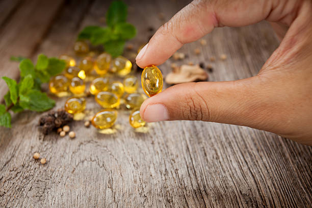 女性はタラ肝油オメガ3ゲルカプセルを保持します - fish oil vitamin pill cod liver oil nutritional supplement ストックフォトと画像