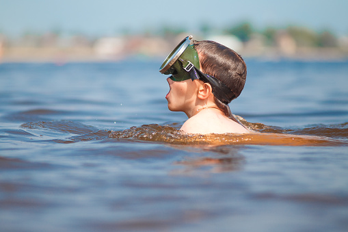 child takes a deep breath mouth before snorkeling into the water. side view