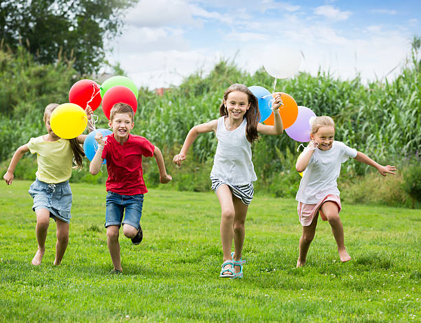 istock Four smiling kids running on green lawn 585054614
