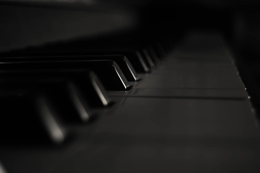 Electric piano with sheet music, microphone and laptop. Home studio. Blurred foreground.