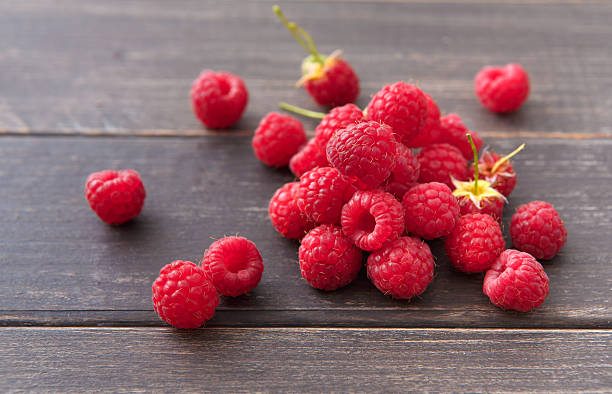 istock Red fresh raspberries on brown rustic wood background 585057184