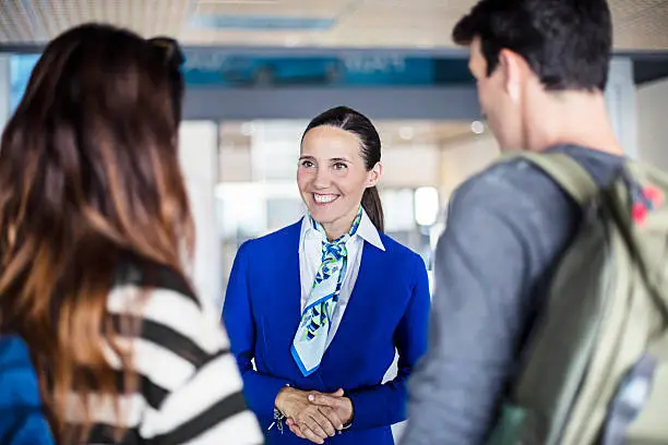 Photo of Air hostess helping young couple at airport